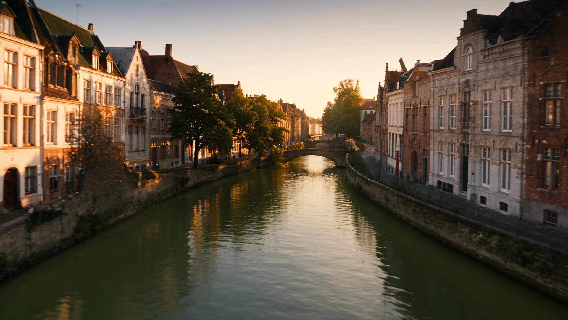 The canal in Bruges at dusk, lamps reflected on still water.